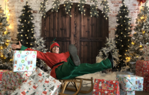 One of Santa's elves sitting on a sleigh surrounded by presents