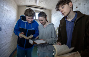 A group of visitors trying to work out a clue during The Cell Escape Room